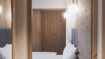 A bedroom with a wooden wall, a bed with white bedding, and a modern light fixture.