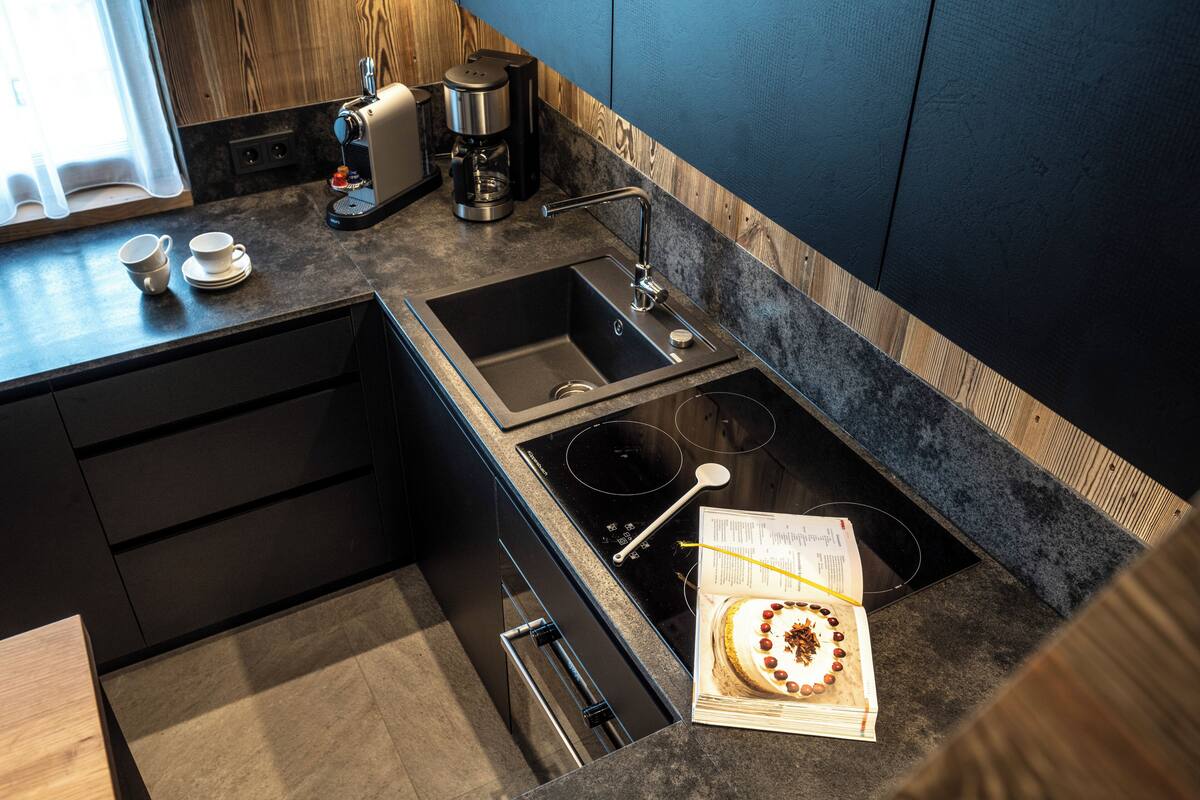 Una cocina moderna con pileta integrada, estufa y cafetera.