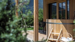A wooden cabin with a deck, a window, and a view of mountains. - Kessler's Mountain Lodge (Naz Sciaves)
