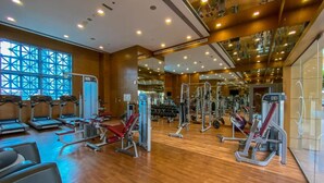 Ett gym med löpband, styrketräningsmaskiner och en vägg täckt med speglar.