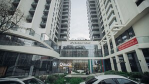 Un edificio moderno con facciata in vetro, un cartello con la scritta 'SABAWAK' in alto e un cartello 'Bravo' sottostante.