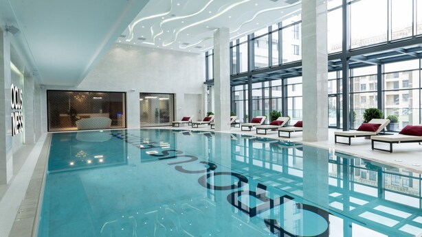 Un'ampia piscina interna con lettini prendisole e un moderno design del soffitto.