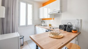 Una cocina moderna con armarios blancos, una encimera de madera y un ventanal con cortinas.