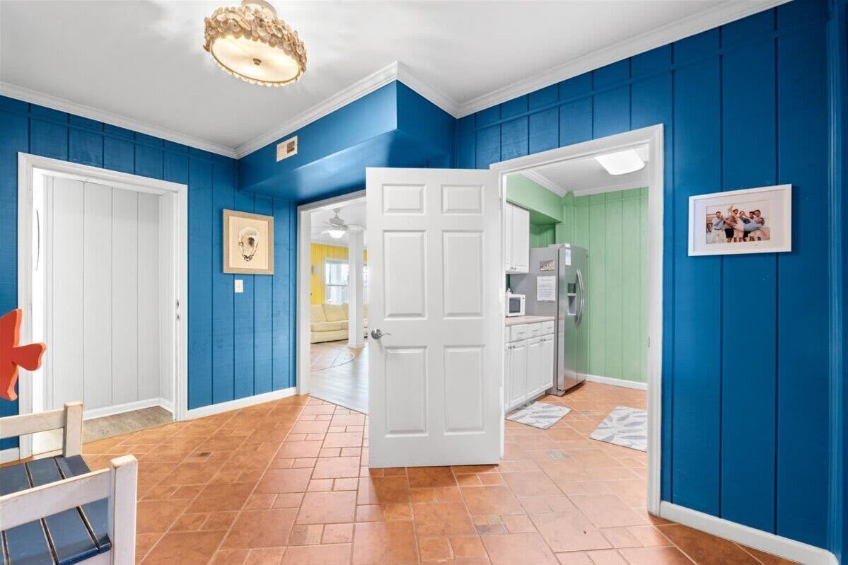 A hallway with blue walls, white doors, and a tiled floor.