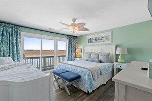 Une chambre à coucher avec un lit, un banc, une table de chevet, une lampe et une vue sur la mer.