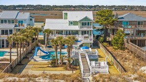Un complexe hôtelier situé en bord de mer, composé de plusieurs bâtiments, d’une piscine et d’un toboggan aquatique.