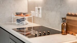 Une cuisine moderne dotée d’une cuisinière intégrée, d’un plan de travail blanc et d’un porte-serviettes avec des serviettes pliées.