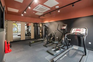 Une salle de sport équipée de divers appareils d’exercice, notamment des tapis de course, un vélo d’appartement et des appareils de musculation.