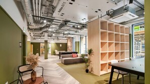 Un espace de bureau moderne avec un sol à motifs en chevrons, un canapé, une table basse et une bibliothèque.