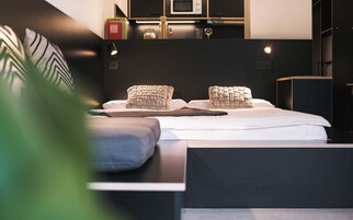 Un dormitorio moderno con una cama bien hecha, una mesita de noche y una estantería empotrada.