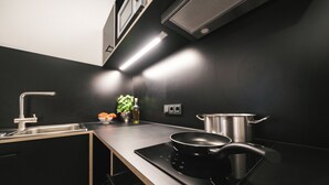 A modern kitchen with a black countertop, stainless steel appliances, and a pot on the stove.