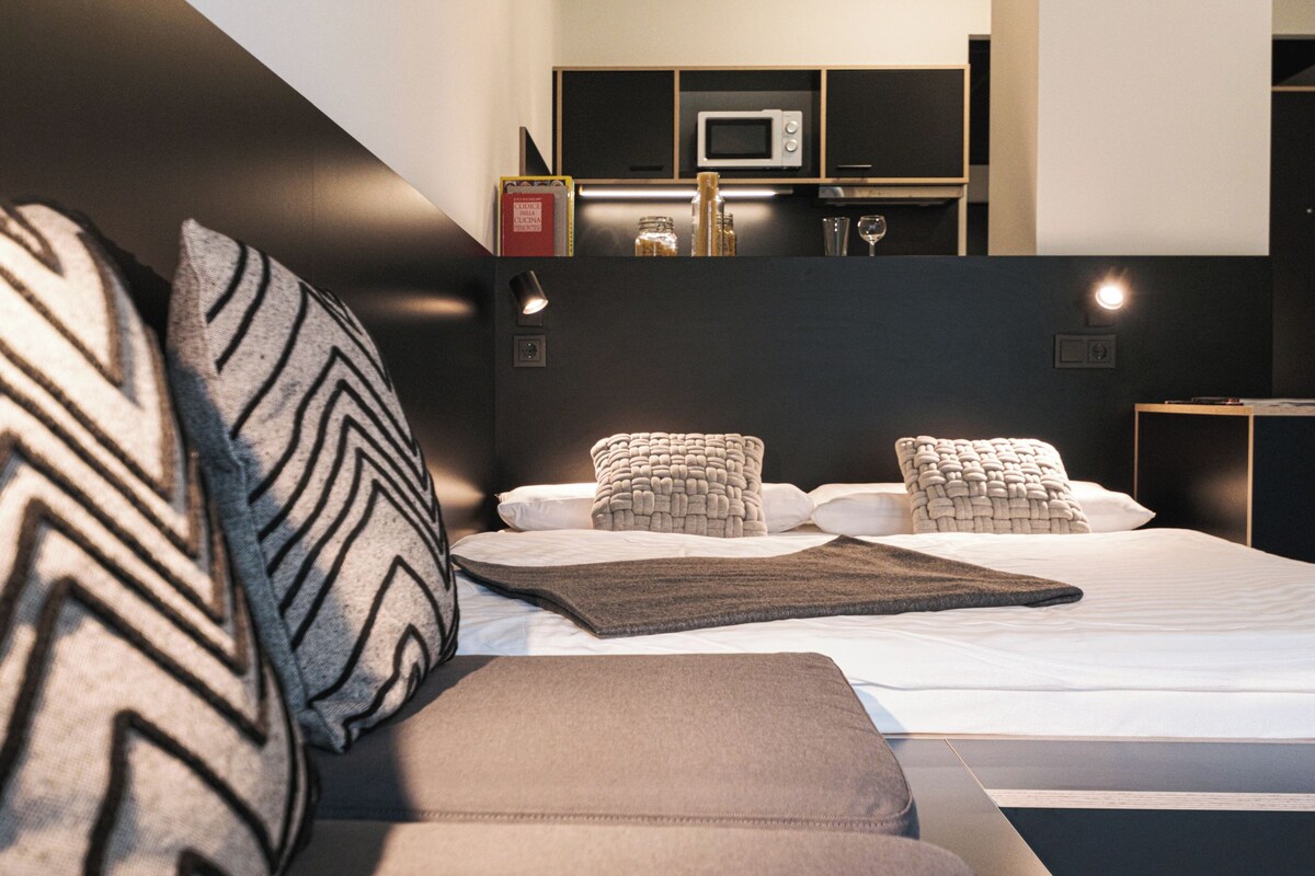 A modern bedroom with a sofa bed, a bedside table, and a built-in TV shelf.