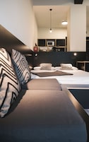 Un dormitorio moderno con sofá cama, mesita de noche y estante empotrado para la televisión.