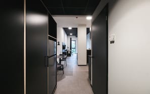 Ein moderner Büroarbeitsplatz mit einem langen Gang, der zu einem Schreibtischbereich mit Computer und Stuhl führt.