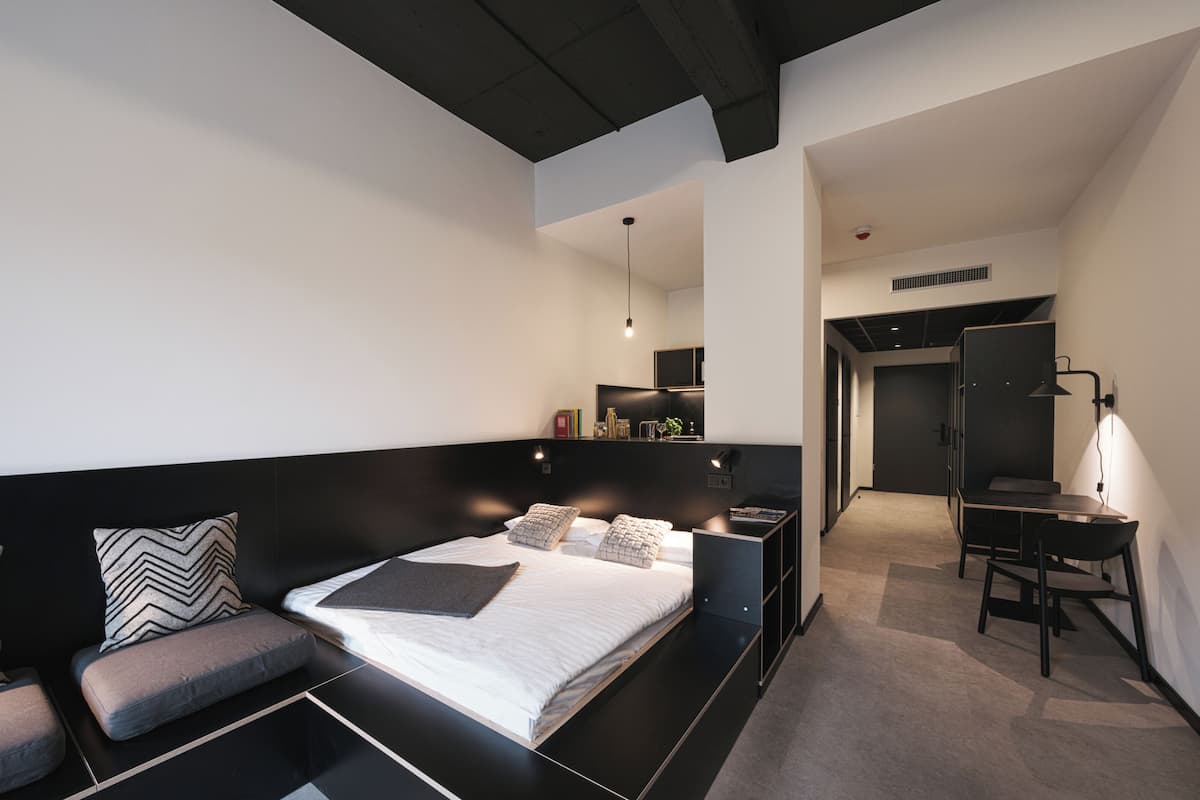Un dormitorio moderno con una cama grande, un escritorio y una zona de estar.