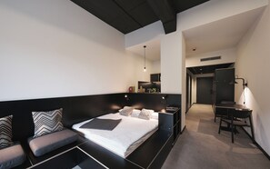Une chambre moderne avec un grand lit, un bureau et un coin salon.