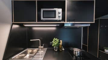 A modern kitchen with a built-in microwave, stainless steel sink, and a small herb garden.