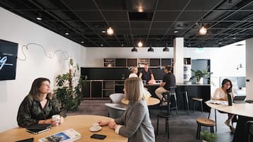 A modern office space with round tables, black chairs, and pendant lighting.