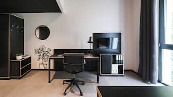 A modern office space with a desk, chair, TV, and storage units.