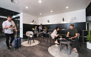 A modern lounge area with seating arrangements, a coffee table, and a potted plant. - Moliving - Design Hotels & Apartments - Free Gym (Neuss)
