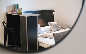 Une petite pièce comprenant un lit, un bureau et une chaise.