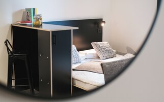 A compact room with a bed, a desk, and a chair.