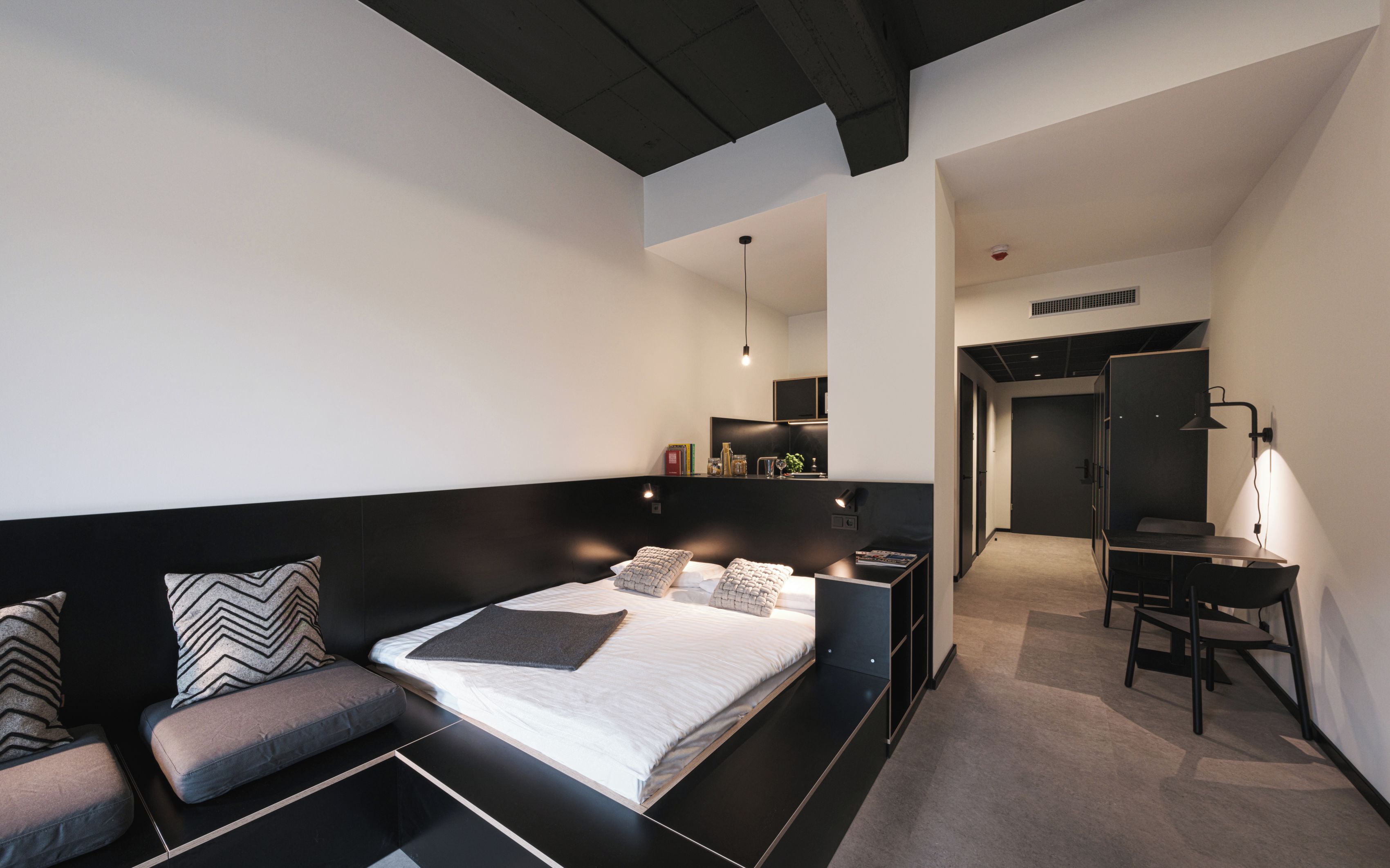 Une chambre moderne avec un grand lit, un bureau et un coin salon.