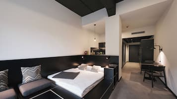 Une chambre moderne avec un grand lit, un bureau et un coin salon.