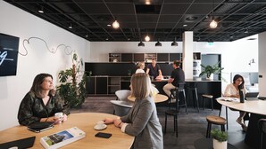 A modern office space with round tables, black chairs, and pendant lighting.