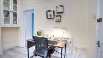 Une pièce comprenant un bureau, une chaise et une lampe fixée au mur.