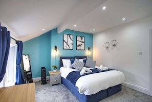 Un dormitorio con cama, mesitas de noche, un espejo y decoración en la pared.