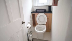 Uma casa de banho pequena com sanita, suporte para toalhas e janela.