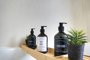 Un estante en el baño con tres botellas de productos para el cuidado corporal.