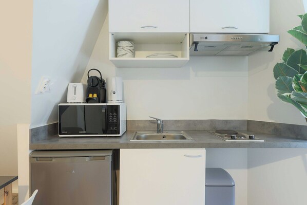 Une cuisine de taille réduite, équipée d’un four à micro-ondes encastré, d’un évier et d’un lave-vaisselle compact.