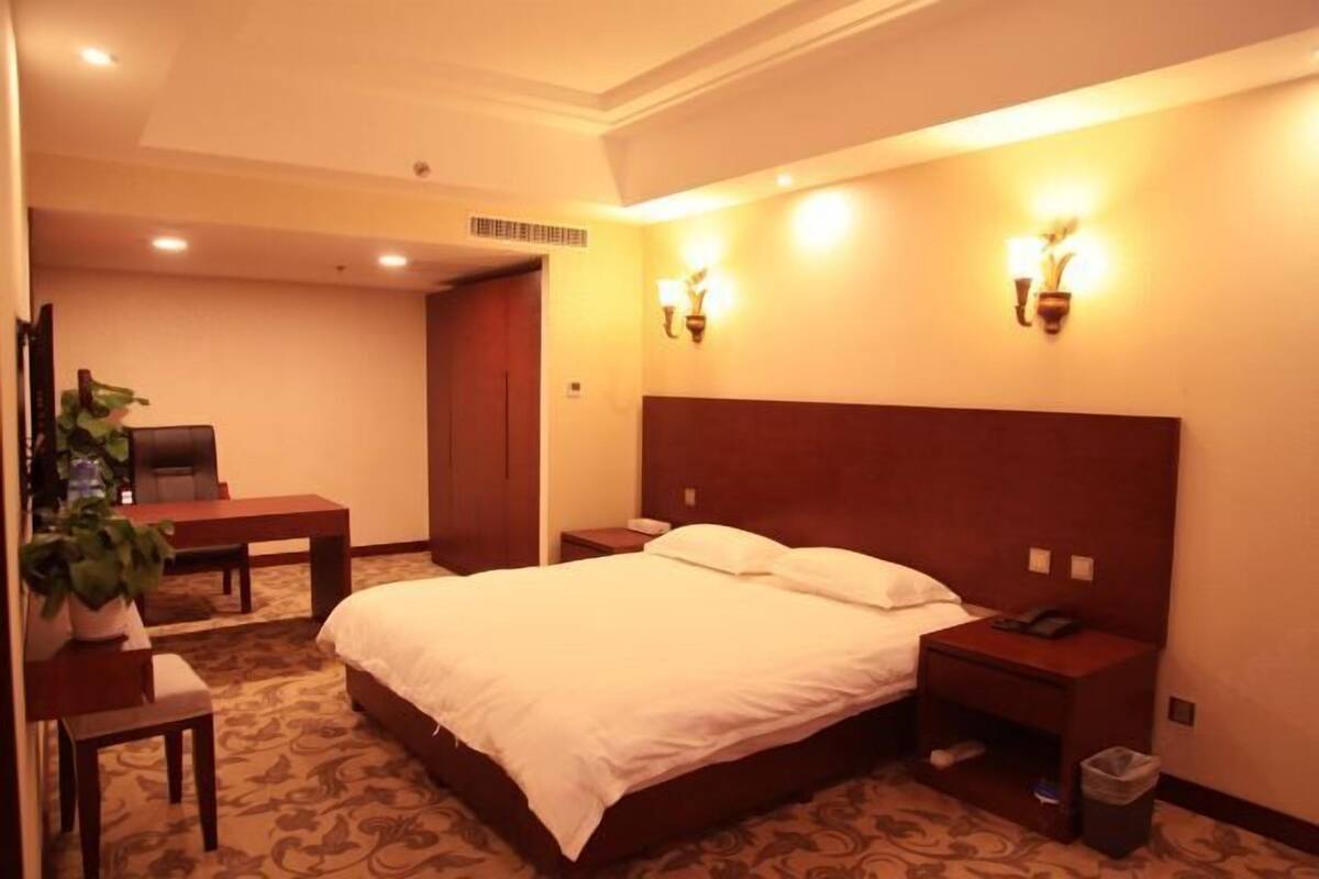 Une chambre d’hôtel avec un grand lit, des tables de chevet, un bureau et une chaise.