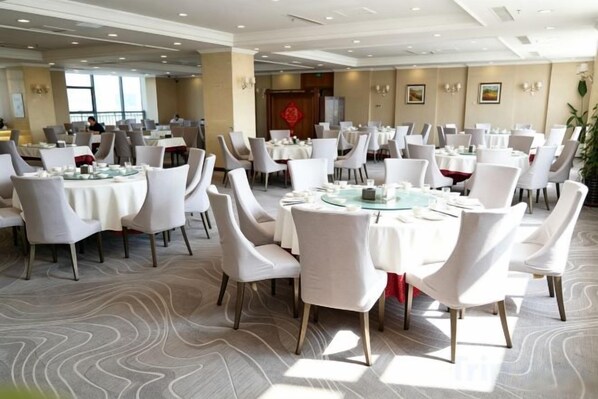A banquet hall with round tables, white chairs, and a patterned carpet. - Shenyang Airport Hotel (SHENYANG)
