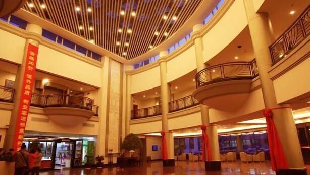 A spacious lobby with multiple levels, a central atrium, and a prominent red banner. - Shenyang Airport Hotel (SHENYANG)