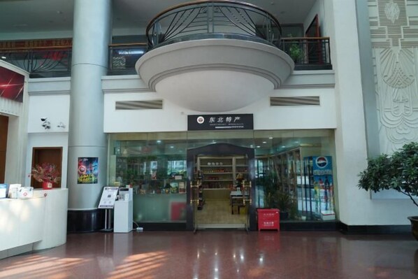 A spacious lobby with a central circular column, a reception desk, and a staircase leading to an upper level. - Shenyang Airport Hotel (SHENYANG)