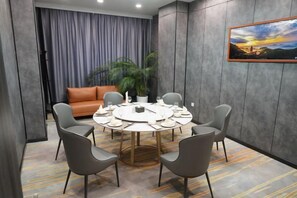 Une salle de conférence avec une table ronde, six chaises, un canapé et une plante en pot.