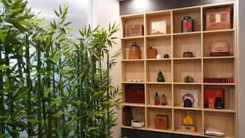 A room with a bamboo plant, wooden shelves, and various items including a clock, books, and decorative objects.