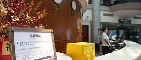 A reception desk with a sign, a clock, and a decorative plant.
