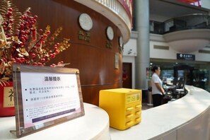 A reception desk with a sign, a clock, and a decorative plant. - Shenyang Airport Hotel (SHENYANG)