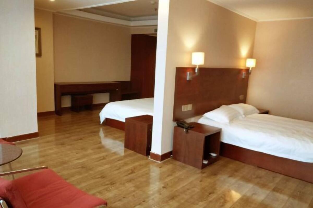Une chambre d’hôtel avec deux lits, une tête de lit en bois, une petite table et une chaise rouge.