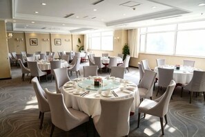 Een vergaderzaal met ronde tafels, stoelen en een groot raam.