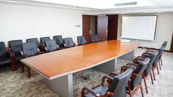 A conference room with a long table and chairs, a projector screen, and a carpeted floor.