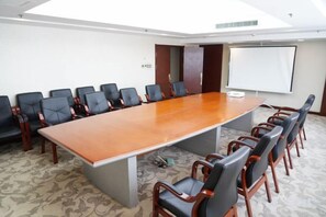 A conference room with a long table and chairs, a projector screen, and a carpeted floor. - Shenyang Airport Hotel (SHENYANG)