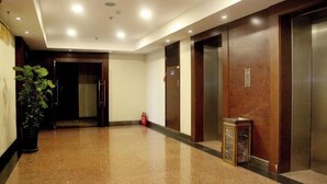 A clean, well-lit hallway with polished floors, wooden doors, and a small potted plant. - Shenyang Airport Hotel (SHENYANG)