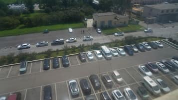 Un estacionamiento con varias filas de coches aparcados y un edificio al fondo.
