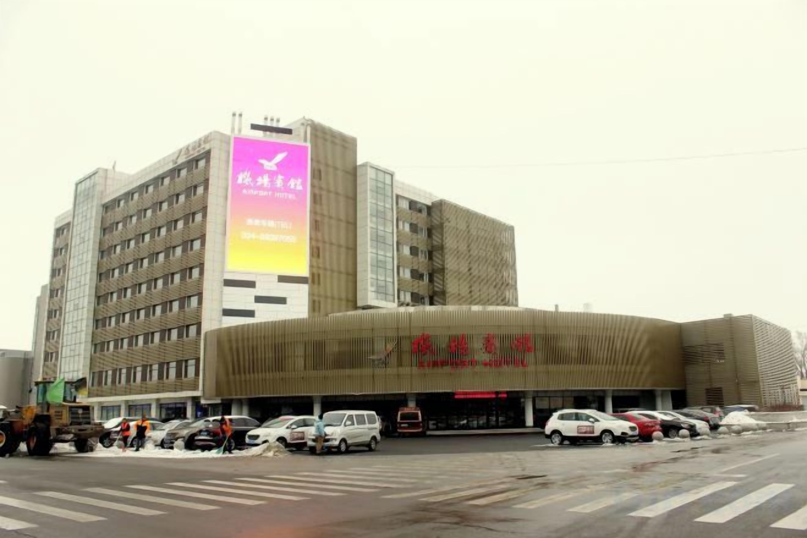 A multi-story building with a large sign on the side and a curved entrance.