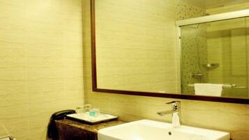 A bathroom with a white sink, a mirror, and a glass shower enclosure.
